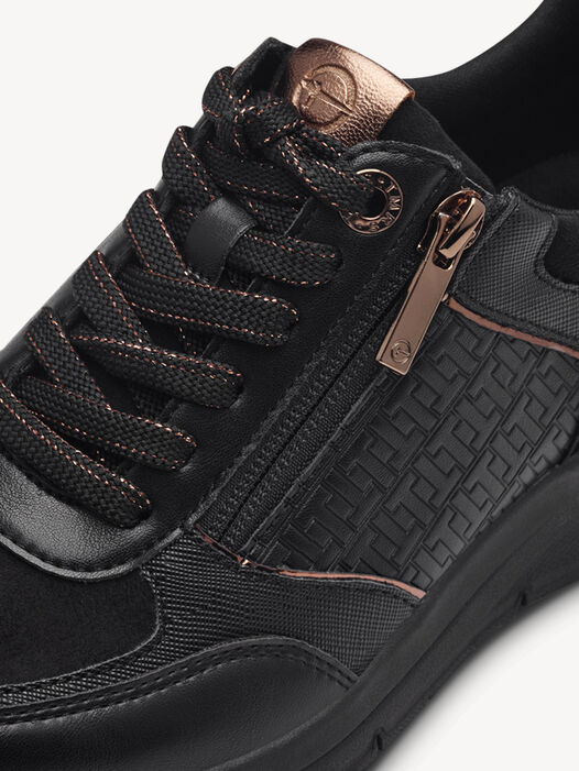 Close-up van veters en koperen rits op zwarte sneakers