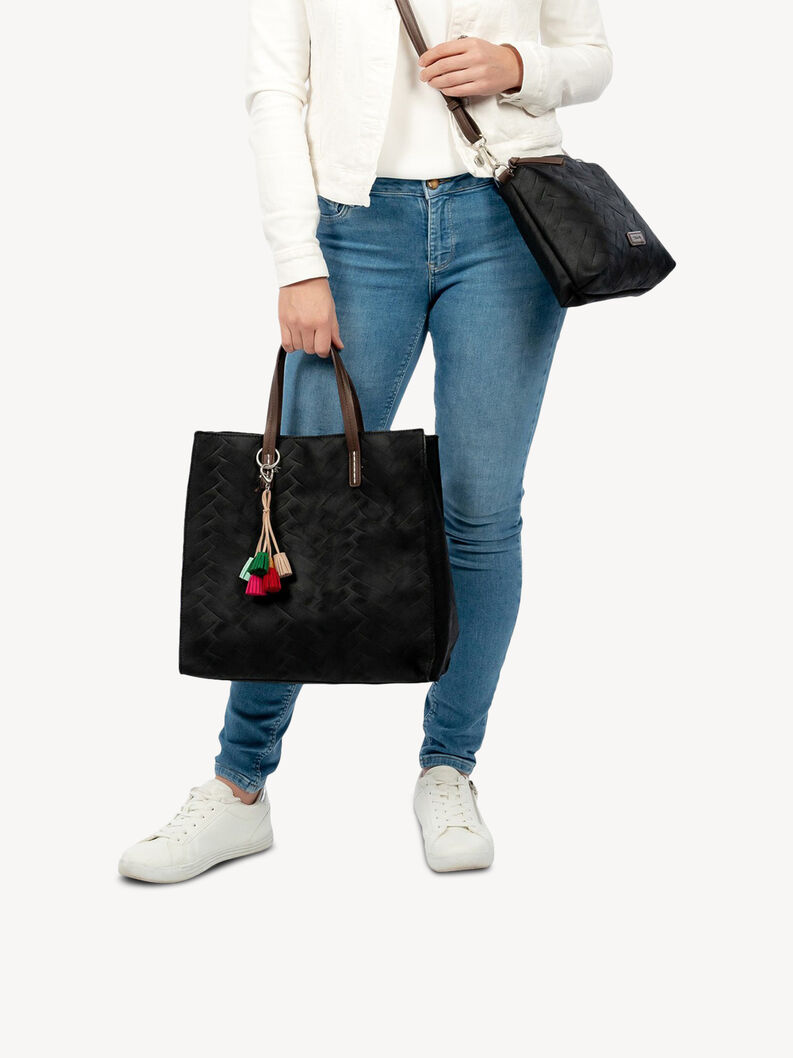 Frau h&auml;lt schwarze Kunstledertasche mit bunten Quasten