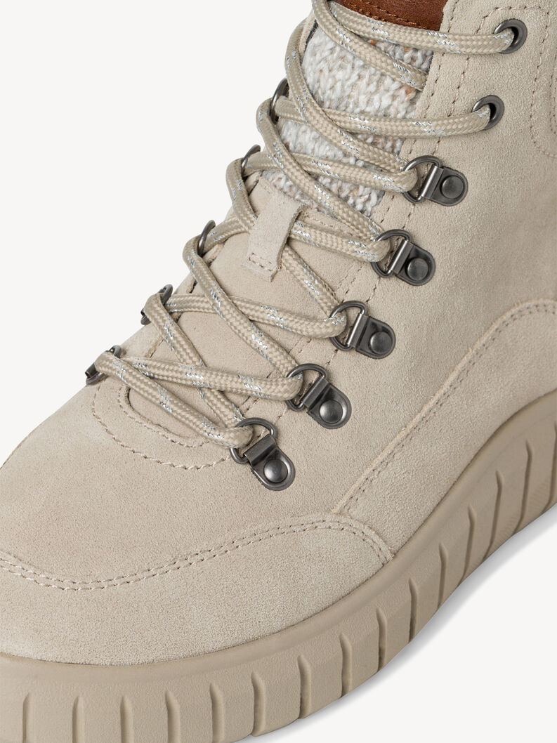 Gros plan sur les lacets en daim beige et la couture avant de la bottine